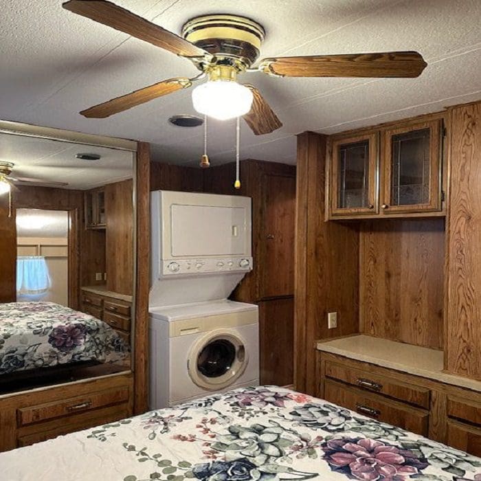 An rv with a bed and a washer and dryer.