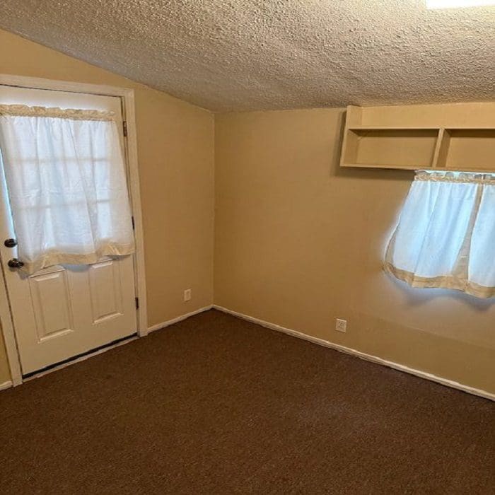 An empty room with a door and a window.