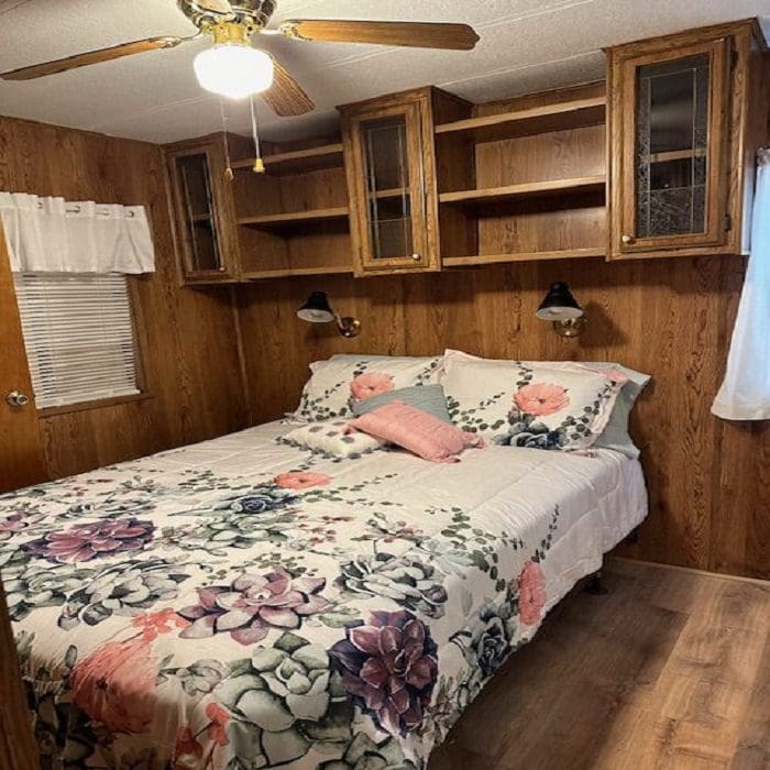 A bedroom in a rv with wood paneling and a bed.