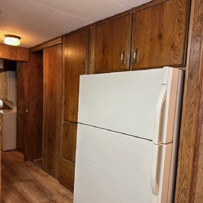An empty kitchen with wood cabinets and a refrigerator.