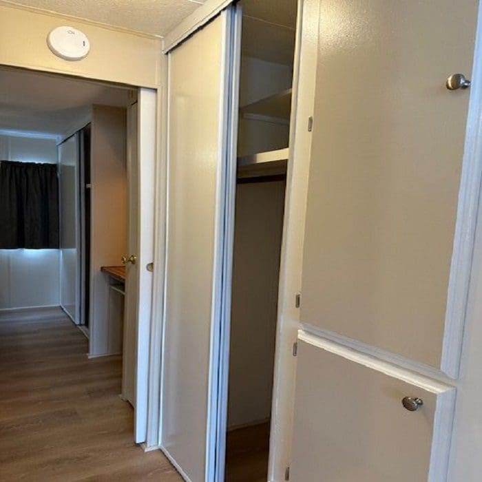 A room in a mobile home with closets and doors.
