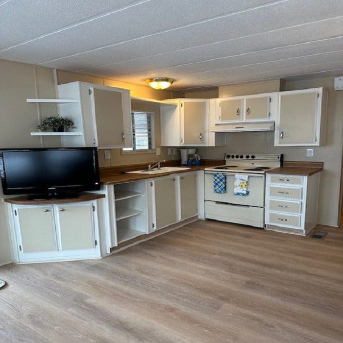 A kitchen with white cabinets and a tv.